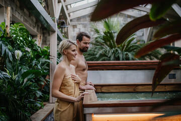 Beautiful couple standing by hot tub, enjoying romantic wellness weekend in spa. Concept of Valentine's Day.