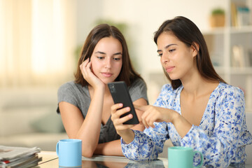 Serious friends checking phone at home