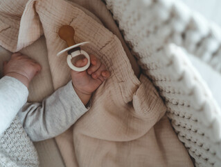 Baby with a nipple. Close up of baby hands with pacifier. Focus is on hands. Newborn sleeping on a...