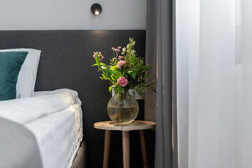 a vase of flowers in the bedroom on the bedside table next to the bed