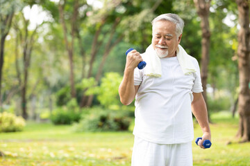 senior man exercising and lifting dumbbells in the park