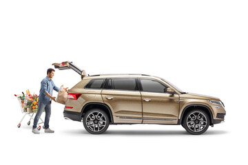 Young man with a shopping cart loading groceries in the trunk of a SUV © Ljupco Smokovski