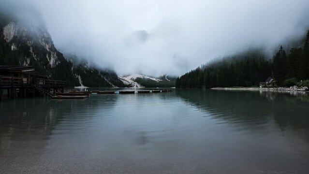 Braies lake misty morning with boats floating in the Dolomites ethereal alpine valley