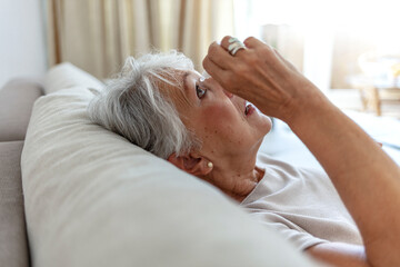 Old woman putting eye drop, closeup view of an elderly person using a bottle of eye drops in her eyes. A sick old woman suffering from irritated eyes, optical symptoms. Health concept.