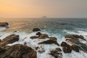 Coast scene with big tides in the rocks and keelung island in the horizon