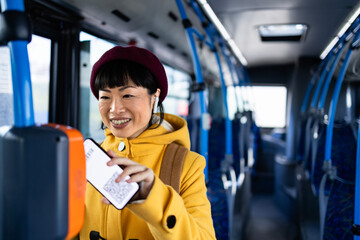 Beautiful woman passenger using her phone to validate digital ticket inside public bus...