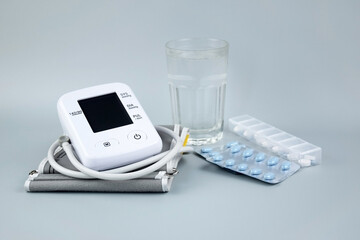 Digital blood pressure tonometer and pack of pills on a blue background with copy space.