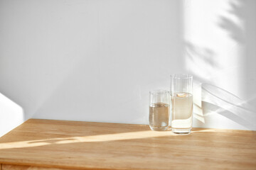 A water cup and shadow on a table in the sunlight.