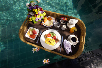 Set of floating breakfast tray in swimming pool. Breakfast in swimming pool, floating breakfast set in tray