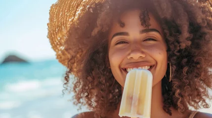 Rolgordijnen Portrait of a young smiling African American woman eating a popsicle ice cream on hot summer day at the beach © Keitma