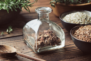 Bottle of dry medicinal bark and herbs for making healing infusion or tincture. Bowls of dried medicinal plants and wooden mortar of fresh healing herbs on background. Alternative herbal medicine.