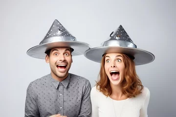 Fototapeten man and woman holding metallic hats, exaggerated emotions, futuristic spaceship, ufos in the sky, conspiracy theory concept © zgurski1980