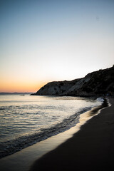 Fototapeta premium A tranquil scene as people enjoy a sunset swim in the calm sea, bathed in the warm hues of dusk, creating a serene coastal atmosphere.