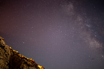 A breathtaking coastal scene as the Milky Way adorns the night sky over the sea and mountain,...