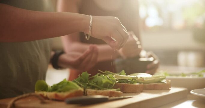 Couple, hands and salt on bread for cooking, seasoning or preparing food, snack or breakfast meal at home. Closeup of hungry people sprinkling spice on lettuce, wheat or sandwich in kitchen on table