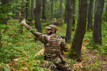 An elite soldier, camouflaged and stealthily navigating through dangerous woodland terrain,...