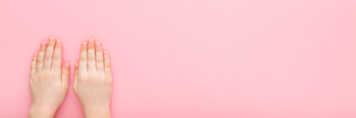 Little girl hands on light pink table background. Pastel color. Closeup. Point of view shot. Wide...