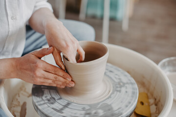 Pulling out the walls of a clay product on a potter's wheel. Hands of a Ceramist creating pottery...
