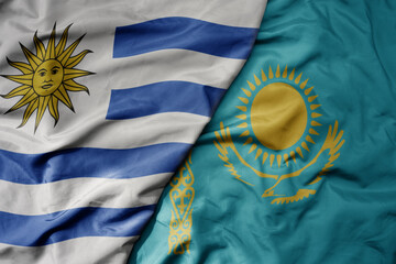 big waving national colorful flag of kazakhstan and national flag of uruguay .