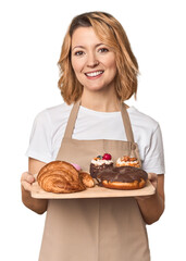 Middle-aged Caucasian woman baker with pastries happy, smiling and cheerful.