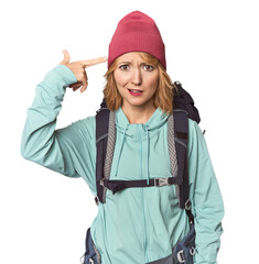 Middle-aged Caucasian woman with hiking gear showing a disappointment gesture with forefinger.