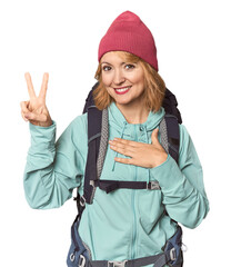 Middle-aged Caucasian woman with hiking gear taking an oath, putting hand on chest.