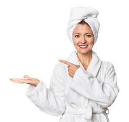 Caucasian woman in bathrobe and towel excited holding a copy space on palm.