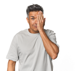 Middle-aged Latino man having fun covering half of face with palm.