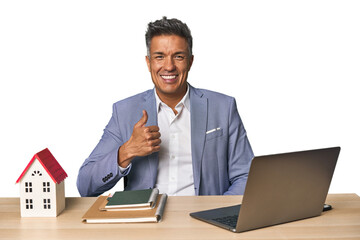 Middle-aged Hispanic businessman with real estate theme smiling and raising thumb up