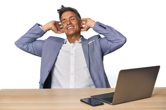 Elegant businessman at desk with laptop stretching arms, relaxed position. - Powered by Adobe
