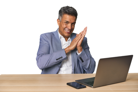 Elegant businessman at desk with laptop feeling energetic and comfortable, rubbing hands confident.