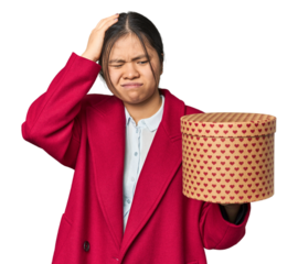 Young Chinese woman holding a heart-filled box being shocked, she has remembered important meeting.