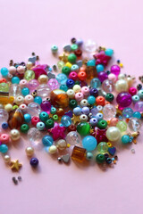 Various colorful beads on bright pink background. Selective focus.