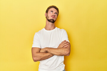 Young Caucasian man on a yellow studio background tired of a repetitive task.