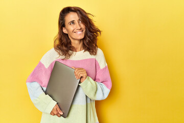 Middle-aged woman using laptop on yellow