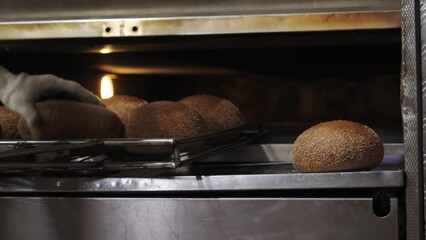 production line of  bakery enterprise. at  production plant for the production of bakery products, an employee uses special shovel to remove ready-made loaves from the oven, close-up. healthy eating