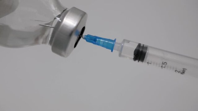 on a white background, a syringe with a needle collects a solution from a bottle. Close-up image of liquid medicine, solution or vaccine in syringe on white background. Healthcare, pandemic concept. 