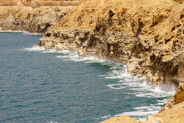 Shore of Dead Sea of Jordan side. Emerald water of  Dead Sea leaves, exposing stepped sandy coast. Traces of dying sea. Spring 2011. Ecology theme.