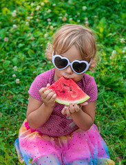 Child girl in the park eats watermelon. Selective focus.