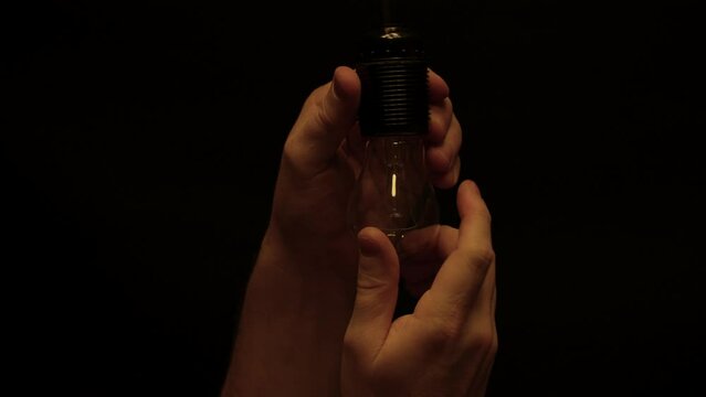 Electrician installing lamp in socket, close-up