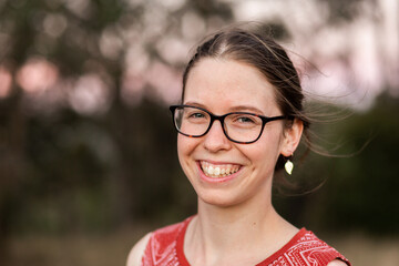 Happy young adult with glasses smiling outside - youth portrait