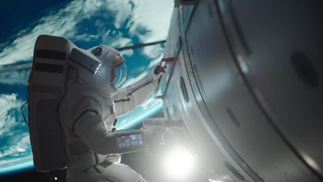 Space Engineer Servicing a Panel on a Communication Satellite with an Automatic Screw Gun. Brave Astronaut Working in Outer Space with Beautiful Blue Planet Earth in the Background