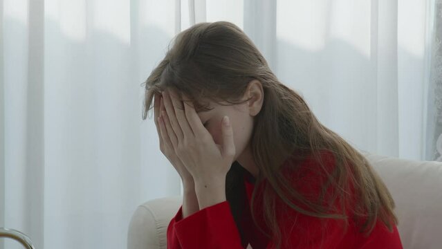Stressed woman covering face with hands, emotional anxiety at home