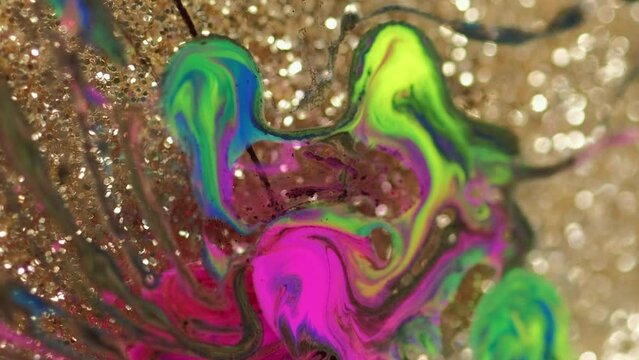 Fluid art texture. Paint water flow. Bright pink green color wet ink mix motion on defocused golden glitter bokeh light surface abstract background.