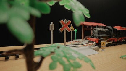 Model of a children's plastic steam train with freight cars stands on the tracks at a railroad station. The atmosphere is ideal for use in children's presentations or toy advertising.