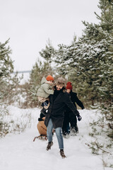 Happy loving family! Father, mother and children are playing and hugging outdoors. Cute little kids and parents on snowy winter walk in nature. Frost winter season concept