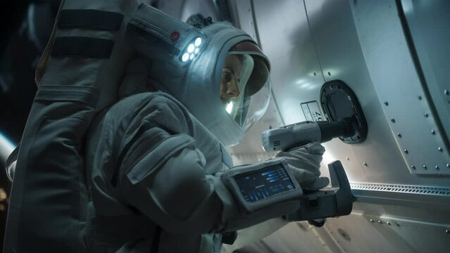 Space Engineer Servicing a Panel on a Communication Satellite with an Automatic Screw Gun. Brave Female Astronaut Working in Outer Space with Beautiful Blue Planet Earth in the Background