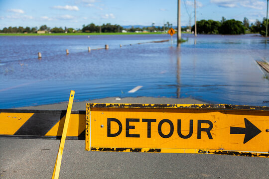 Detour signs blocking a flooded roadway