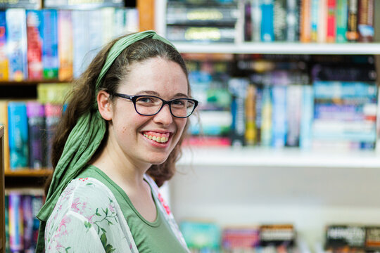 portrait of young woman shopping for second hand books in a store