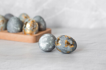 Stylish grey Easter eggs made of marble and concrete with a golden potala on a grey background. Coloring eggs with natural dye karkade tea. . The concept of a happy Easter.